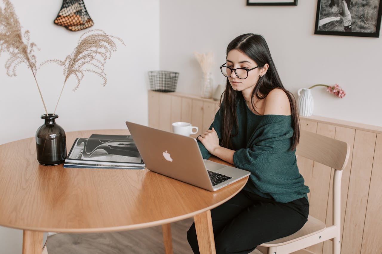 Thoughtful female freelancer watching laptop in light room at home